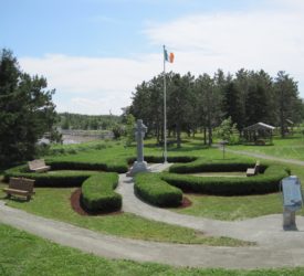 Une croix en pierre et un drapeau irlandais entourés d'une haie en forme de trèfle dans le Parc historique des Irlandaise de L’île Middle