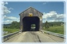 Opening to the Bloomfield Creek covered bridge, beneath a sunny and somewhat cloudy blue sky. 
