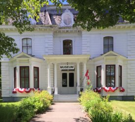 The Charlotte County Archives and Museum, a white symmetrical building decorated with red and white flags.
